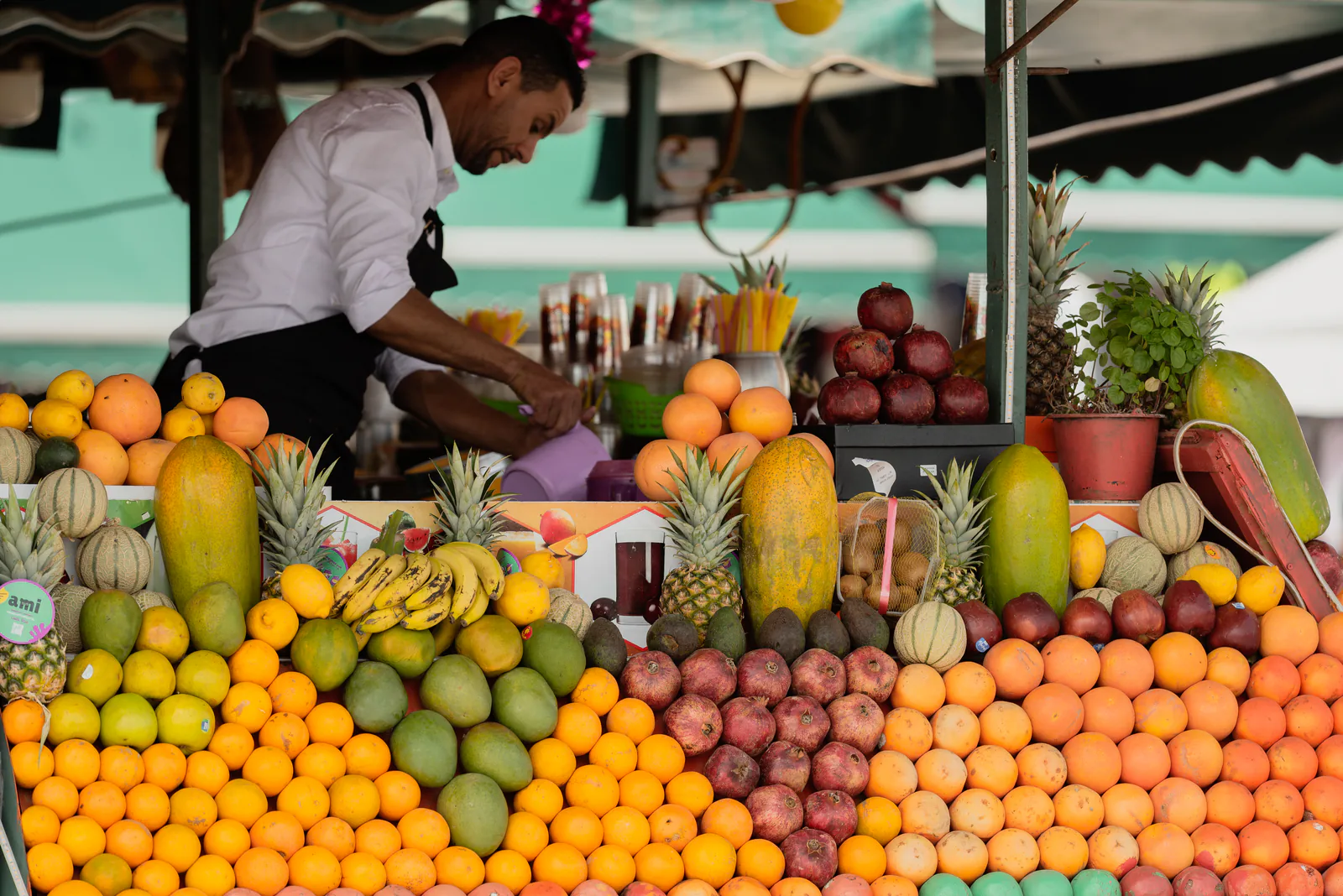 Fruit vendor arranging oranges and pineapples at a souk stall in Marrakech